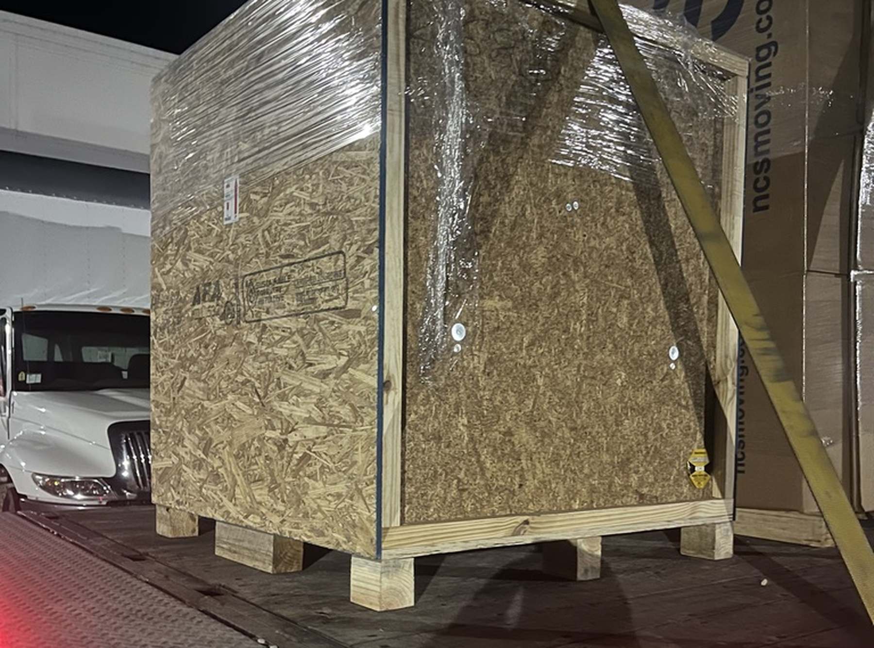 Crated equipment secured on an NCS truck liftgate for loading