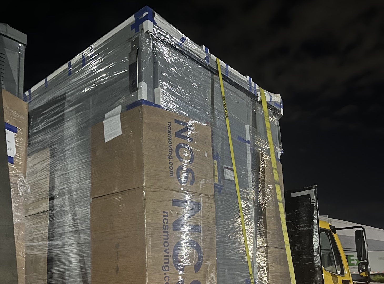Crated equipment shrink wrapped and strapped to a flatbed