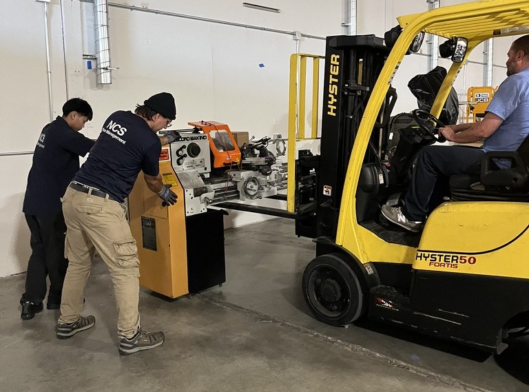 NCS crew moving machine shop equipment into warehouse storage
