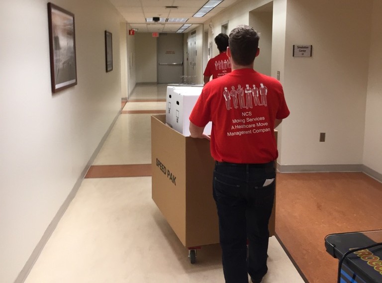 NCS healthcare move crew transporting a crate through a hospital corridor