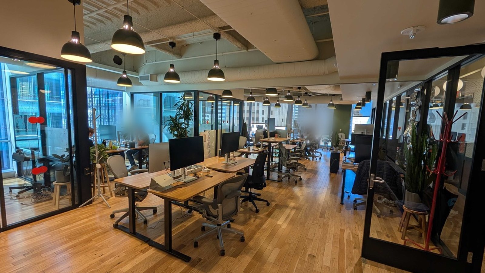 Open-plan office workspace with workstations, monitors, and seating